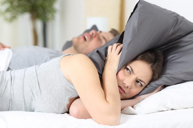 摄图网_304508763_男人打呼噜而他的妻子却用枕头遮耳（企业商用）.jpg